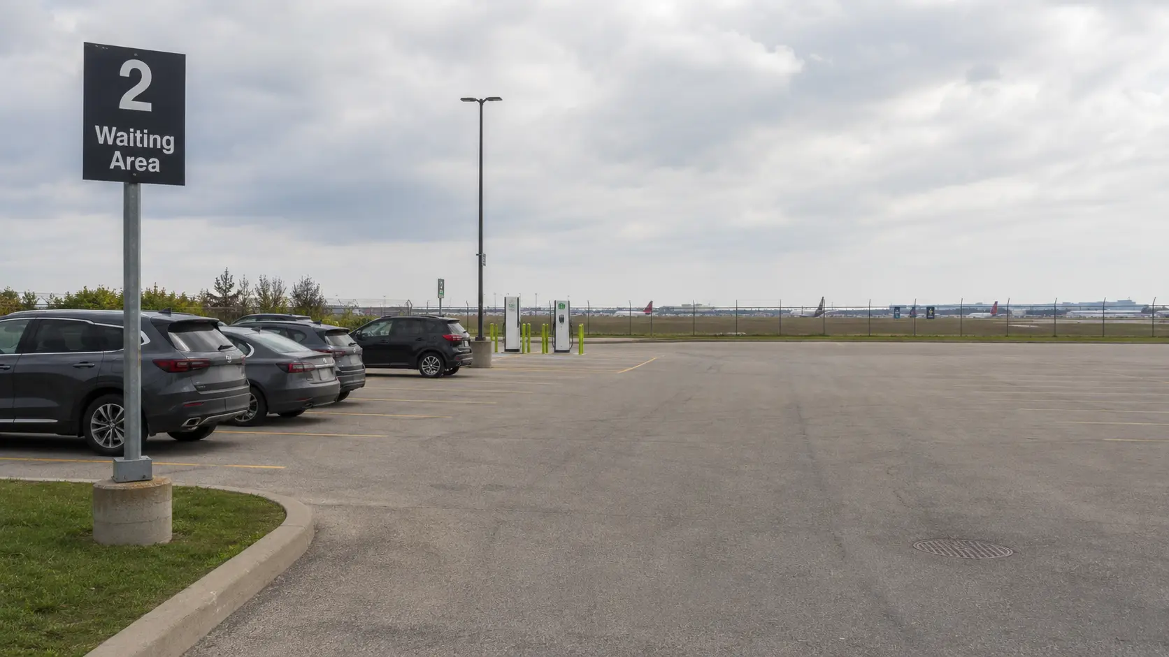 Cars parked in a free waiting area lot near Toronto Pearson Airport with an EV charging station