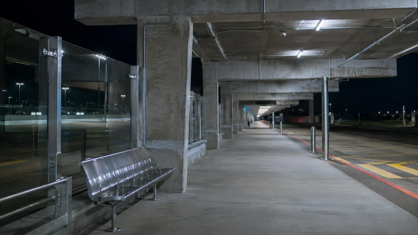 Empty covered public transit bus platform at an airport terminal ground level during overnight hours